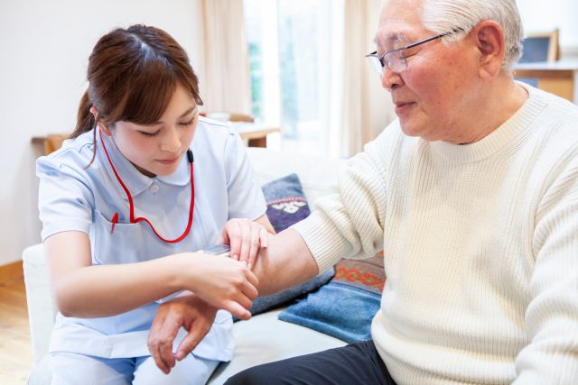 高齢男性の血圧を測る看護師
